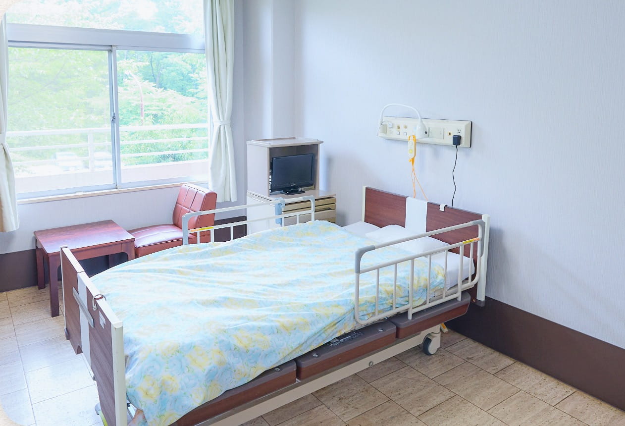 介護ベッドとテレビが備わった施設の居室
