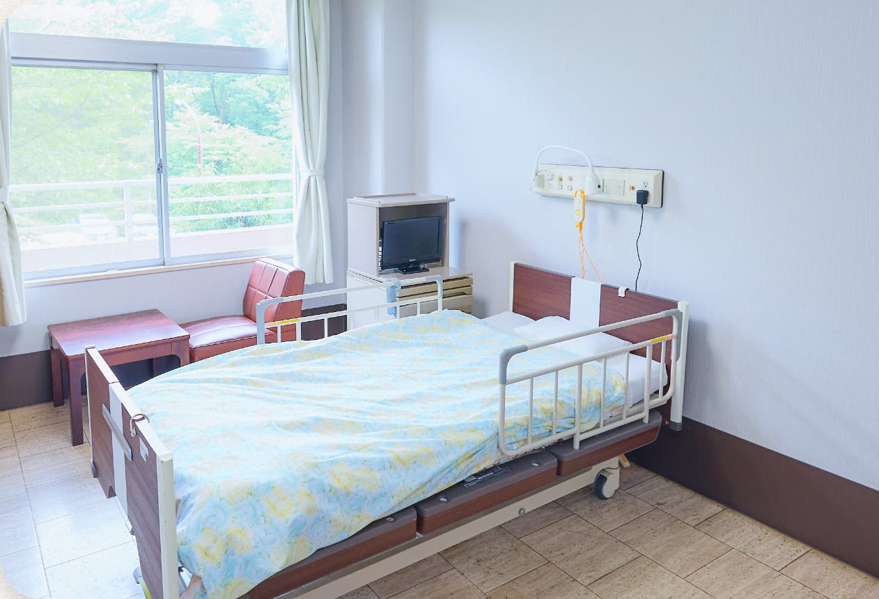 特別養護老人ホームの居室。窓際に介護ベッドとテレビを備えた明るい個室