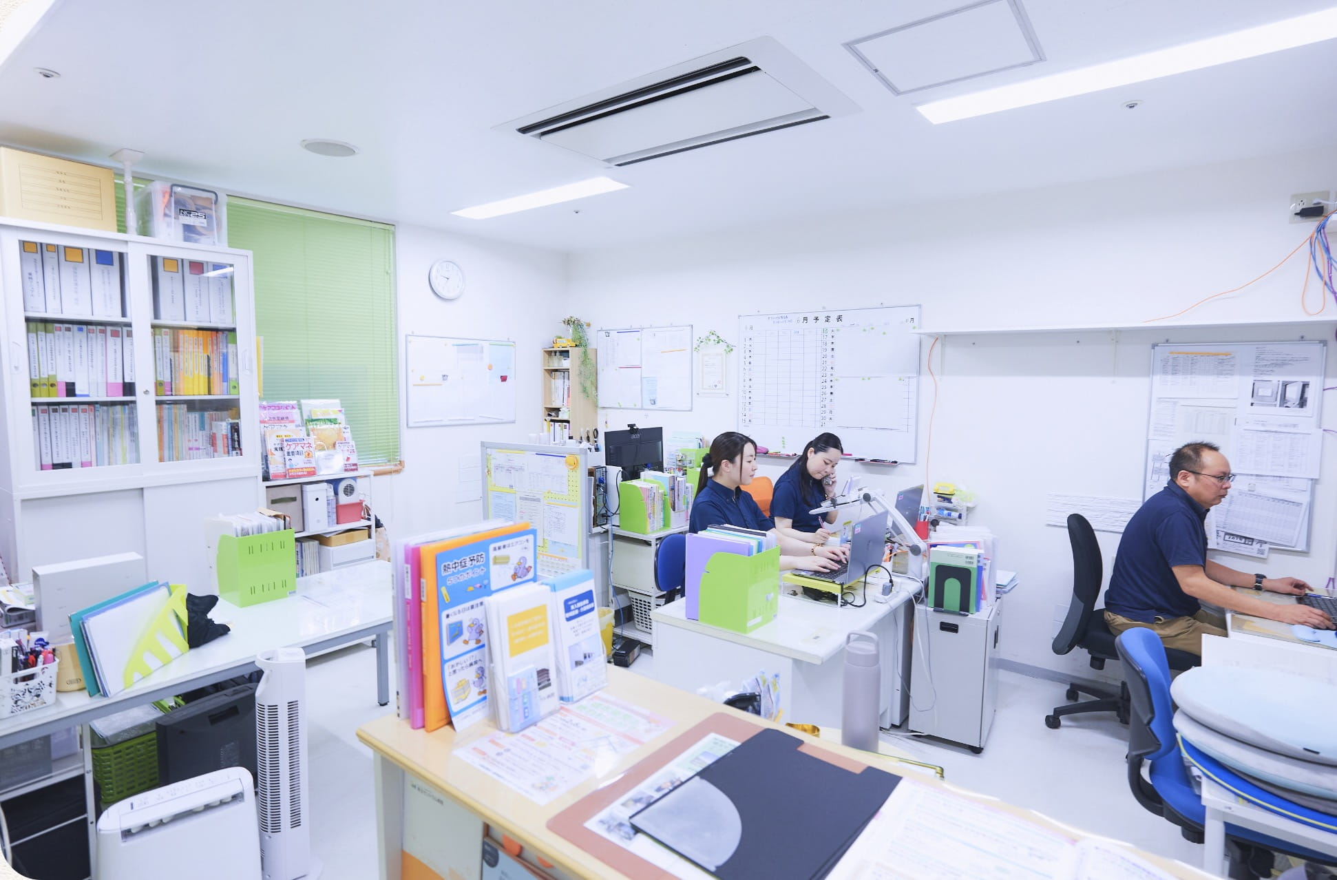 書類棚が並ぶ事務所で業務にあたる居宅介護支援事業所のスタッフ