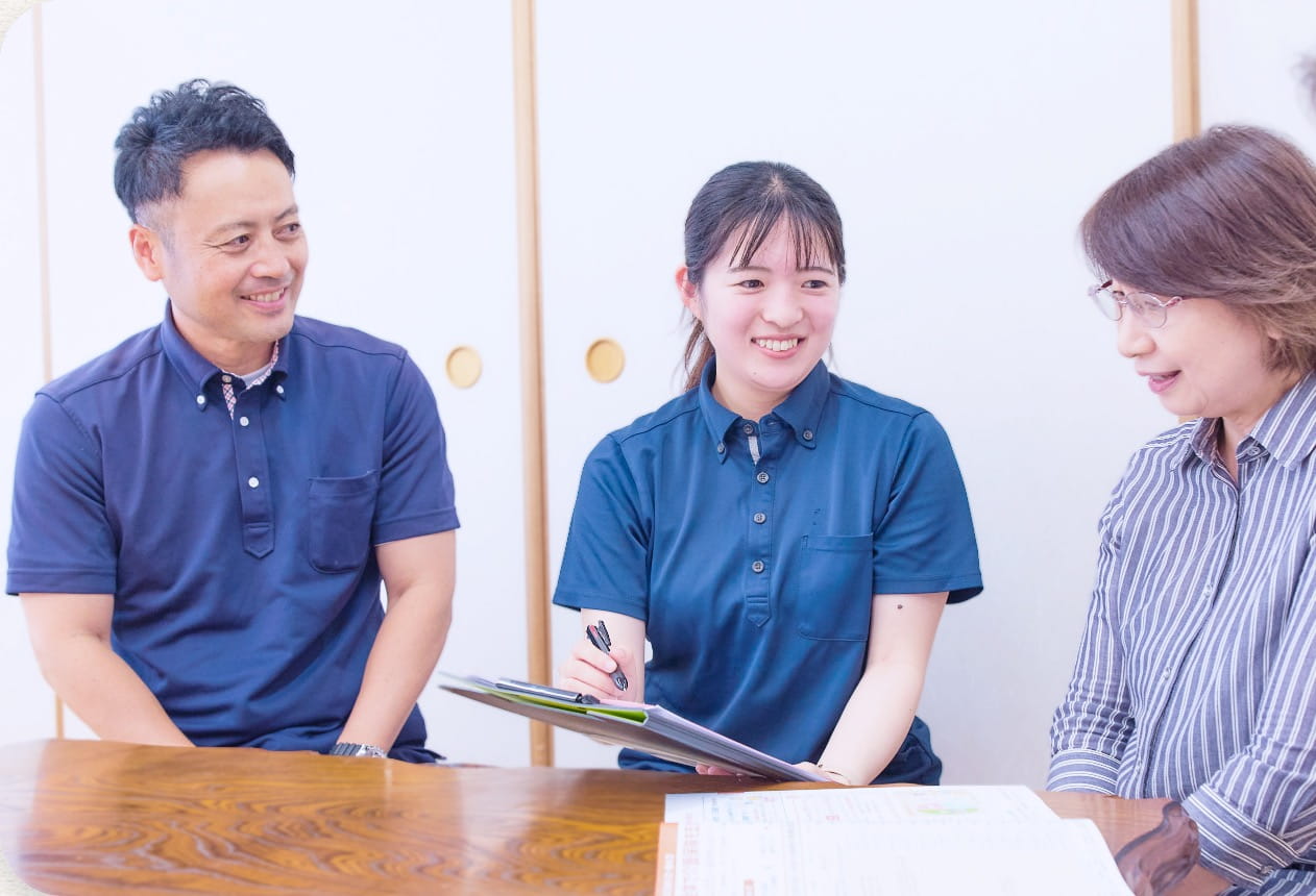 自宅を訪問し利用者と家族に笑顔で応対する居宅ケアマネジャー