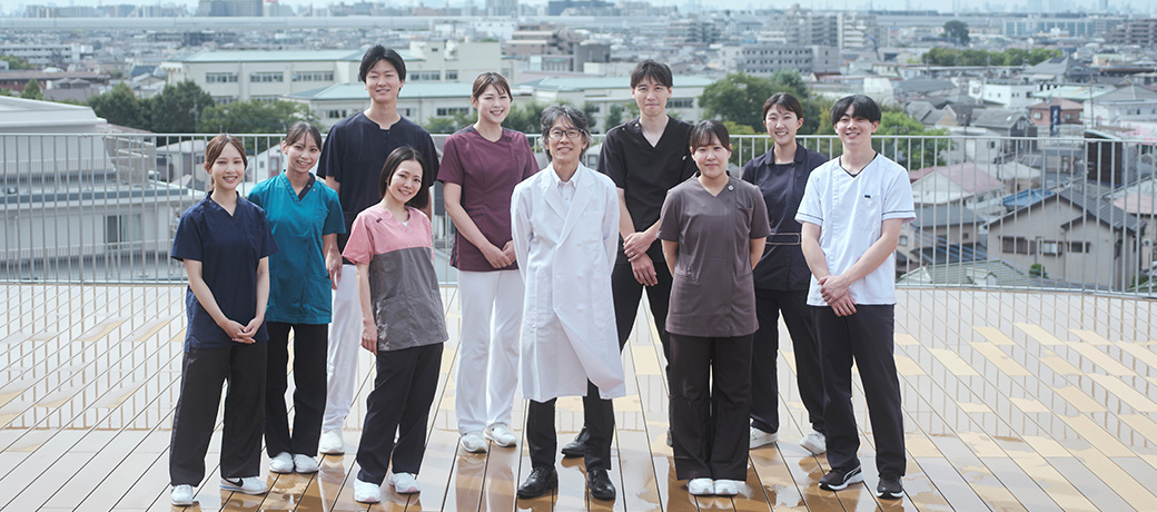 病院の屋上に並ぶイムス埼玉越谷病院の医師・看護師・リハビリスタッフ