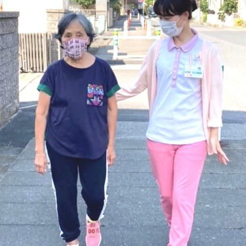 スタッフが付き添って屋外を歩く様子