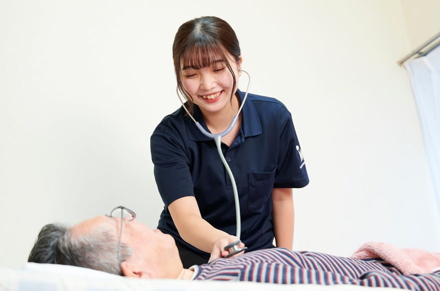 ベッドの患者さまを聴診器で診察する当院の看護師
