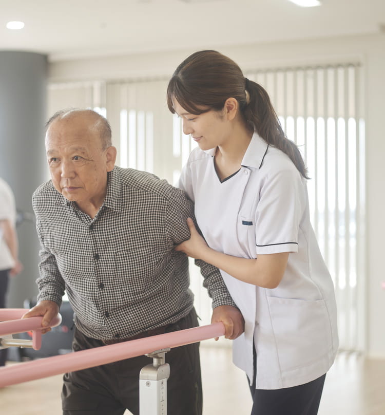 歩行訓練をする患者さまに笑顔で寄り添う看護師