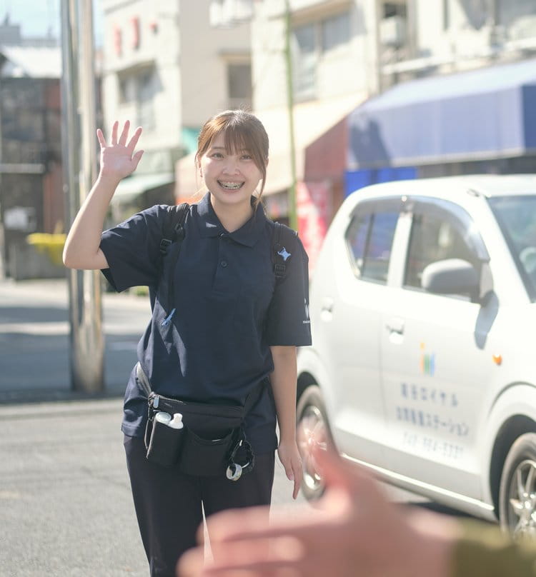 訪問先の玄関先で利用者さまに手を振る訪問スタッフ